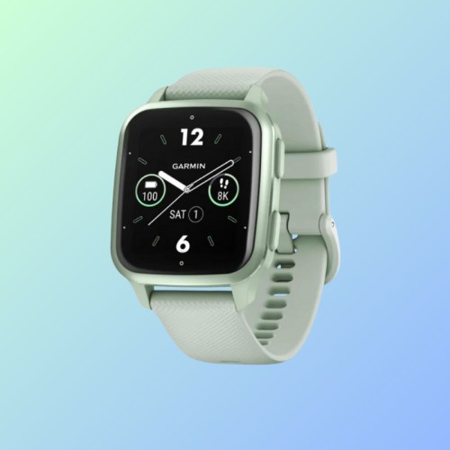 A mint green Garmin smartwatch with a digital display showing time and fitness stats, set against a gradient background.