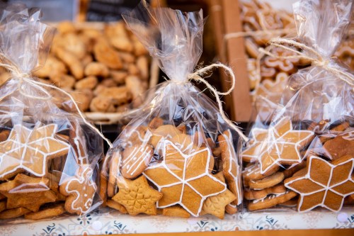 Bags of decorated gingerbread cookies in festive shapes, displayed at a market.