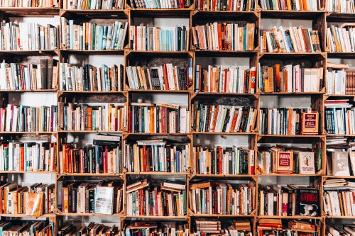 A wooden bookshelf filled with a variety of colorful books arranged neatly in rows.