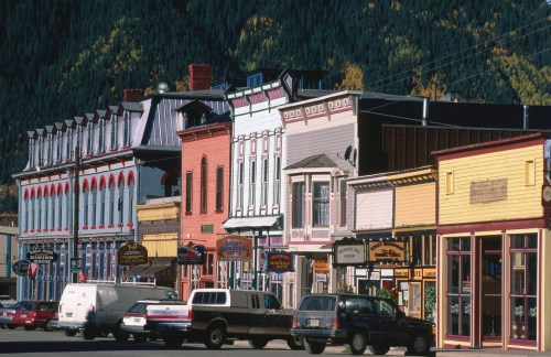 Colorful historic buildings line a street, showcasing vibrant facades and signage in a charming small town.