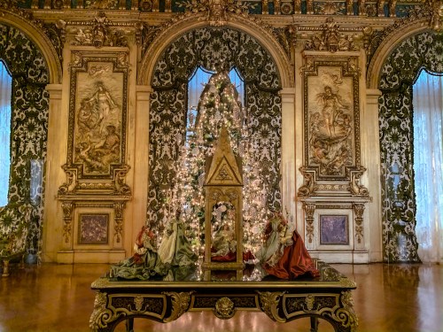 A beautifully decorated room featuring a Christmas tree and ornate wall art, with figures displayed on a table.