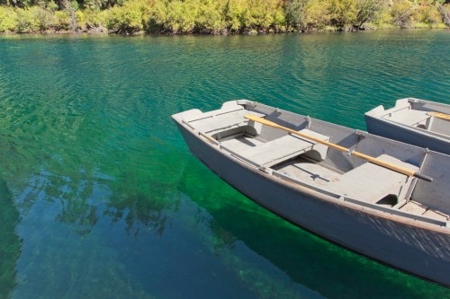 Two wooden boats float on clear, turquoise water surrounded by lush greenery.