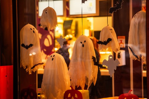 Hanging ghost decorations with bats in a shop window, creating a festive Halloween atmosphere.