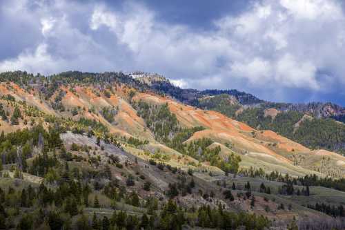 Vibrant orange and green hills under a cloudy sky, showcasing a stunning mountainous landscape.