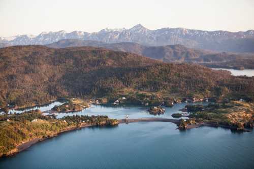 Aerial view of a coastal landscape with mountains, forests, and calm waters, showcasing a serene natural environment.