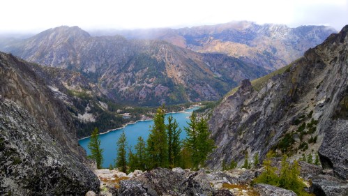 A scenic mountain landscape featuring a turquoise lake surrounded by rugged peaks and lush green trees.