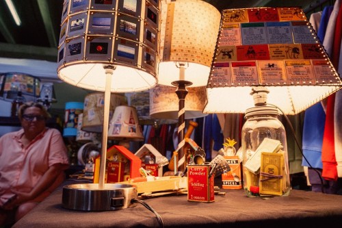 A display of unique lamps and vintage items, with a person sitting in the background.