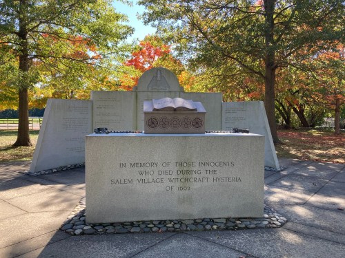 A memorial honoring the victims of the Salem witch trials, featuring a stone tablet and surrounding trees in autumn colors.