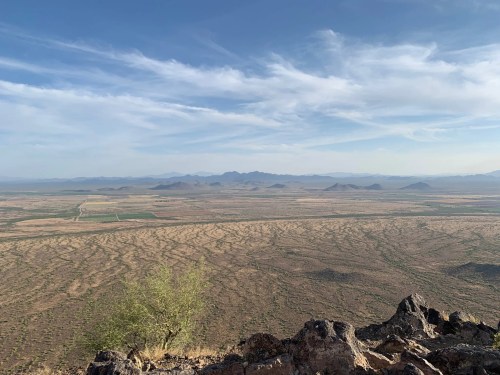 A panoramic view of a desert landscape with mountains in the distance and a clear blue sky.