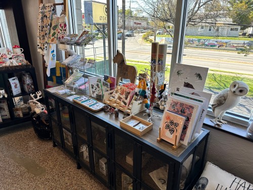 A display of various art prints, stationery, and decorative items in a bright shop window.