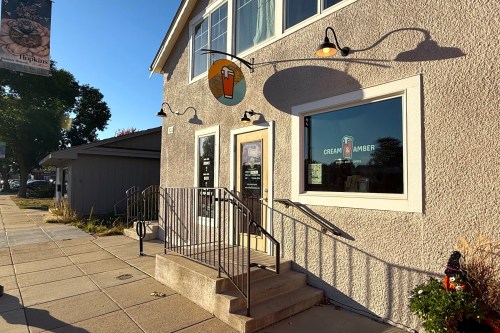 Exterior of a building with a sign reading "Cream & Amber," featuring stairs and outdoor lighting.