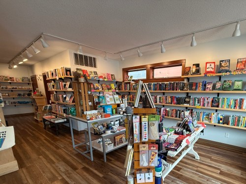 A cozy bookstore interior with shelves filled with books, a display table, and warm lighting.