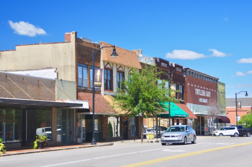 A sunny street view of a small town with historic buildings, shops, and a clear blue sky.