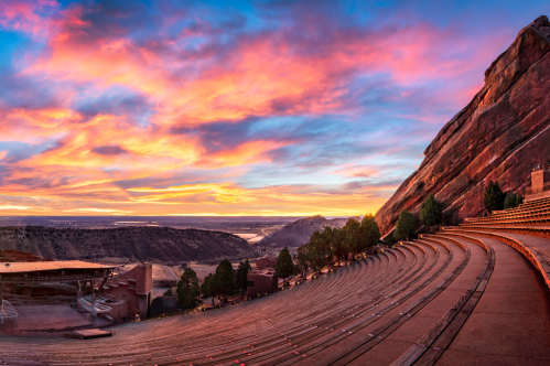 A stunning sunset over Red Rocks Amphitheatre, with vibrant colors illuminating the sky and surrounding rock formations.