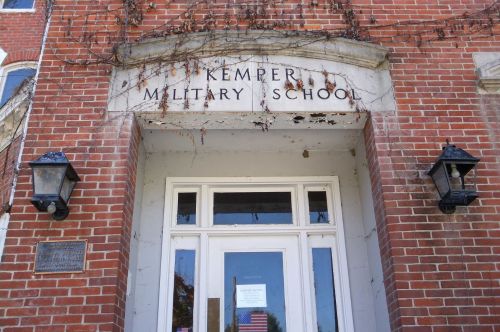 Entrance of Kemper Military School, featuring brick walls, ivy, and a sign above the door.