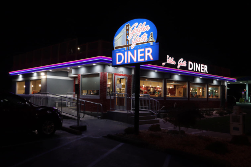 A brightly lit diner at night with a neon sign reading "Golden Gate Diner" and large windows showcasing the interior.