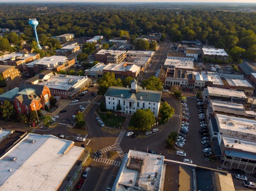 Aerial view of a small town with a courthouse, water tower, and surrounding buildings and parking areas.