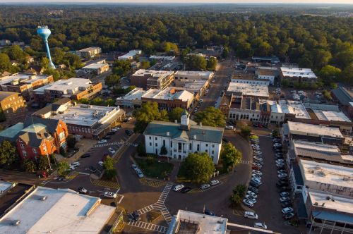 Aerial view of a small town with a central courthouse, surrounding buildings, and a water tower in the background.