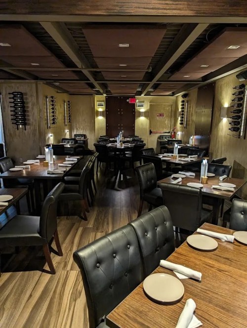 Interior of a modern restaurant featuring dark wood tables, leather chairs, and a warm, inviting atmosphere.