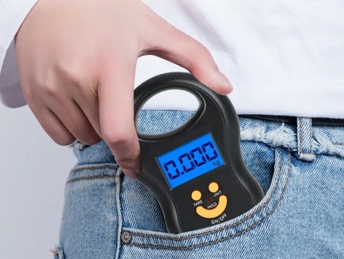 A person holds a digital luggage scale with a blue display, partially tucked into their back pocket.