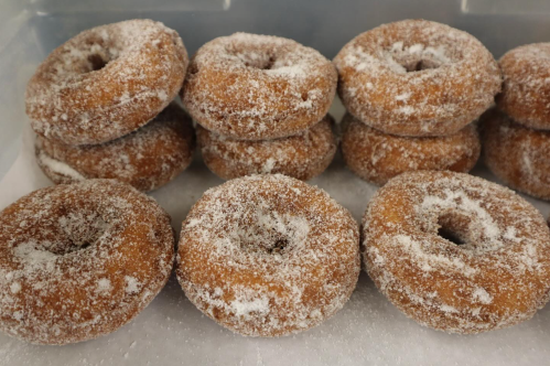 A close-up of a tray filled with sugar-coated donuts stacked neatly.
