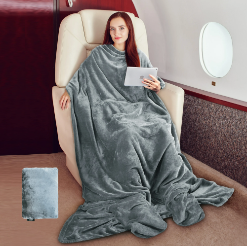 A woman sits comfortably in a plush chair, wrapped in a soft gray blanket, using a tablet in a private jet.