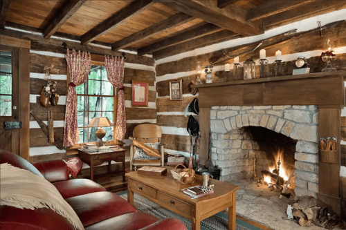 Cozy log cabin interior with a stone fireplace, wooden beams, and rustic decor, featuring a warm, inviting atmosphere.