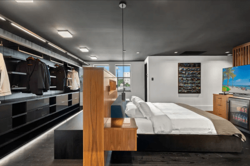 Modern bedroom featuring a sleek design, large closet, and a TV, with a minimalist aesthetic and neutral color palette.