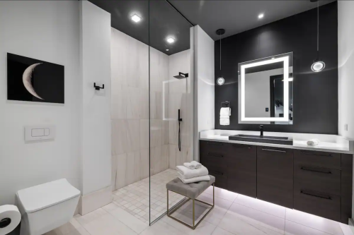 Modern bathroom featuring a glass shower, sleek vanity, and minimalist decor with a moon artwork on the wall.