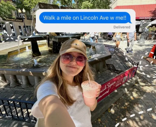 A person takes a selfie by a fountain, holding a drink, with a text message overlay inviting a walk on Lincoln Ave.