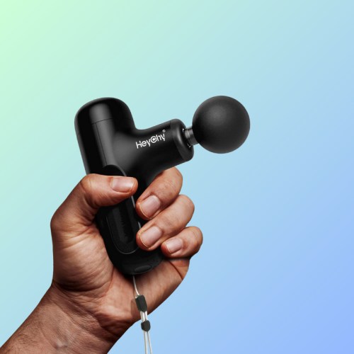 A hand holding a black massage gun against a gradient background.
