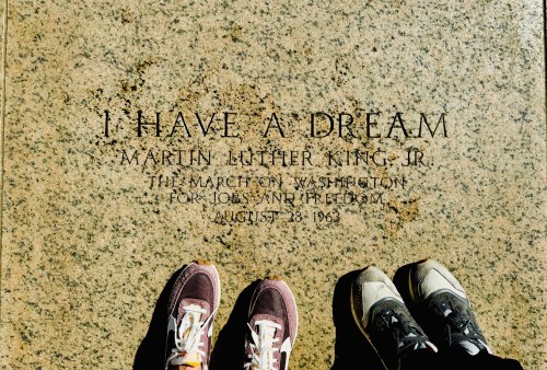 Feet in sneakers stand on a stone engraved with "I Have a Dream" and details of Martin Luther King Jr.'s speech.