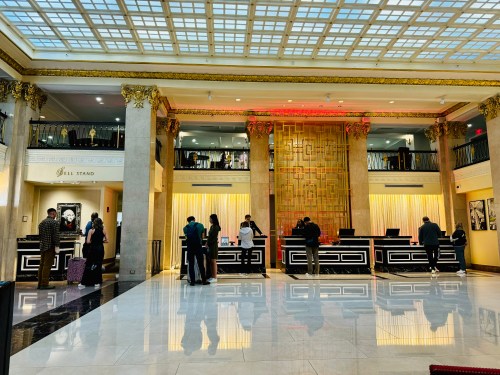 A spacious hotel lobby with elegant decor, featuring a reception area and guests checking in.