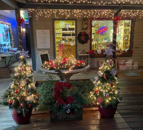 A festive scene featuring two decorated Christmas trees, a fountain, and twinkling lights in a cozy shop setting.