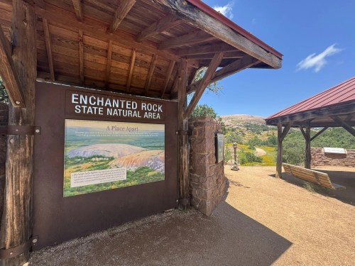 Sign at Enchanted Rock State Natural Area, featuring a painting and information about the park's unique landscape.