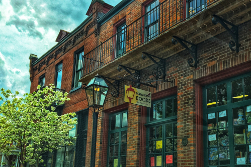 A brick building with a sign reading "Main Street Books," featuring a lamp post and blooming tree in front.