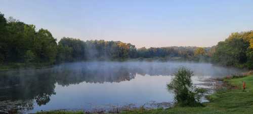 Mist rises off a lake surrounded by fall foliage in Ohio's Cuyahoga Valley National Park.