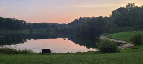 A setting sun reflects off of the greenery-surrounded Indigo Lake in Ohio's Cuyahoga Valley National Park.