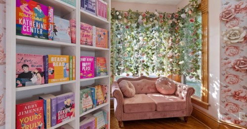 A beautiful regency era-themed room with a velvet pink couch and lots of bookshelves in Ohio.