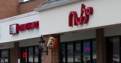 A red sign on a strip mall façade reads "Nudo" in stylized letters.