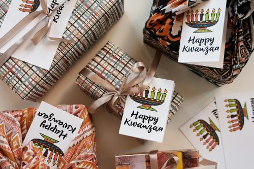 Colorful wrapped gifts with "Happy Kwanzaa" tags and decorative patterns, arranged on a light surface.