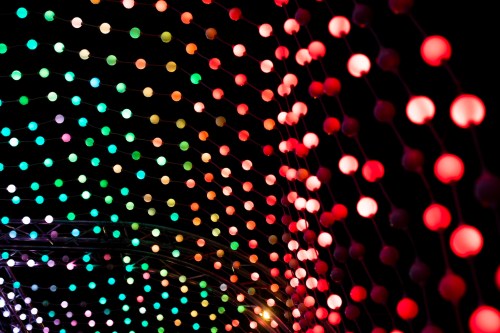 Colorful string lights in red, green, and yellow create a vibrant, festive atmosphere against a dark background.