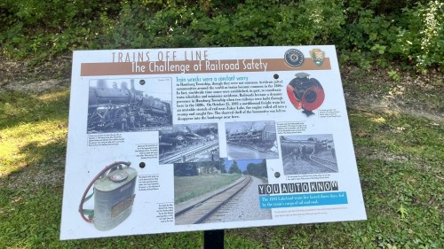 Sign titled "Trains Off Line: The Challenge of Railroad Safety," featuring historical images and information about train safety.