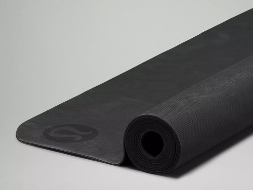 A rolled black yoga mat with a textured surface, partially unrolled on a light gray background.