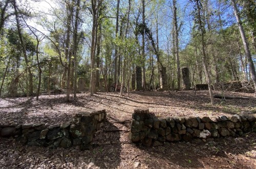 A rock wall and towering pillars were left to ruin in the forest.