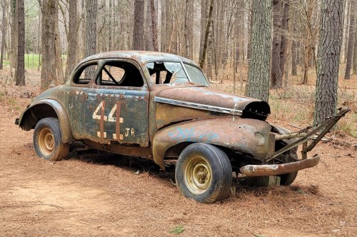 A broken-down car left on the side of the racetrack.