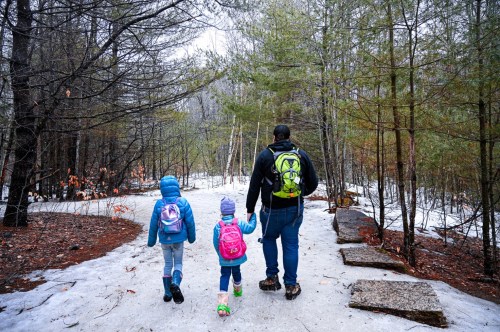 A father and his two daughters are taking off on a trail in the snow.