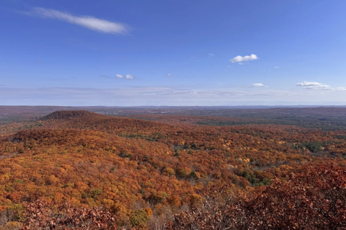 Scenic Mount Norwottuck views along the Robert Frost Trail in Massachusetts. The view from above looks down on orange and red foliage.
