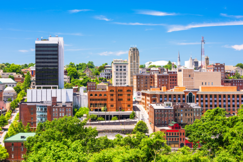 View of Lynchburg, Virginia skyline with trees and blue sky.