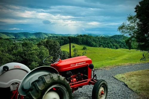 Red vintage tracker overlooking green farmland.